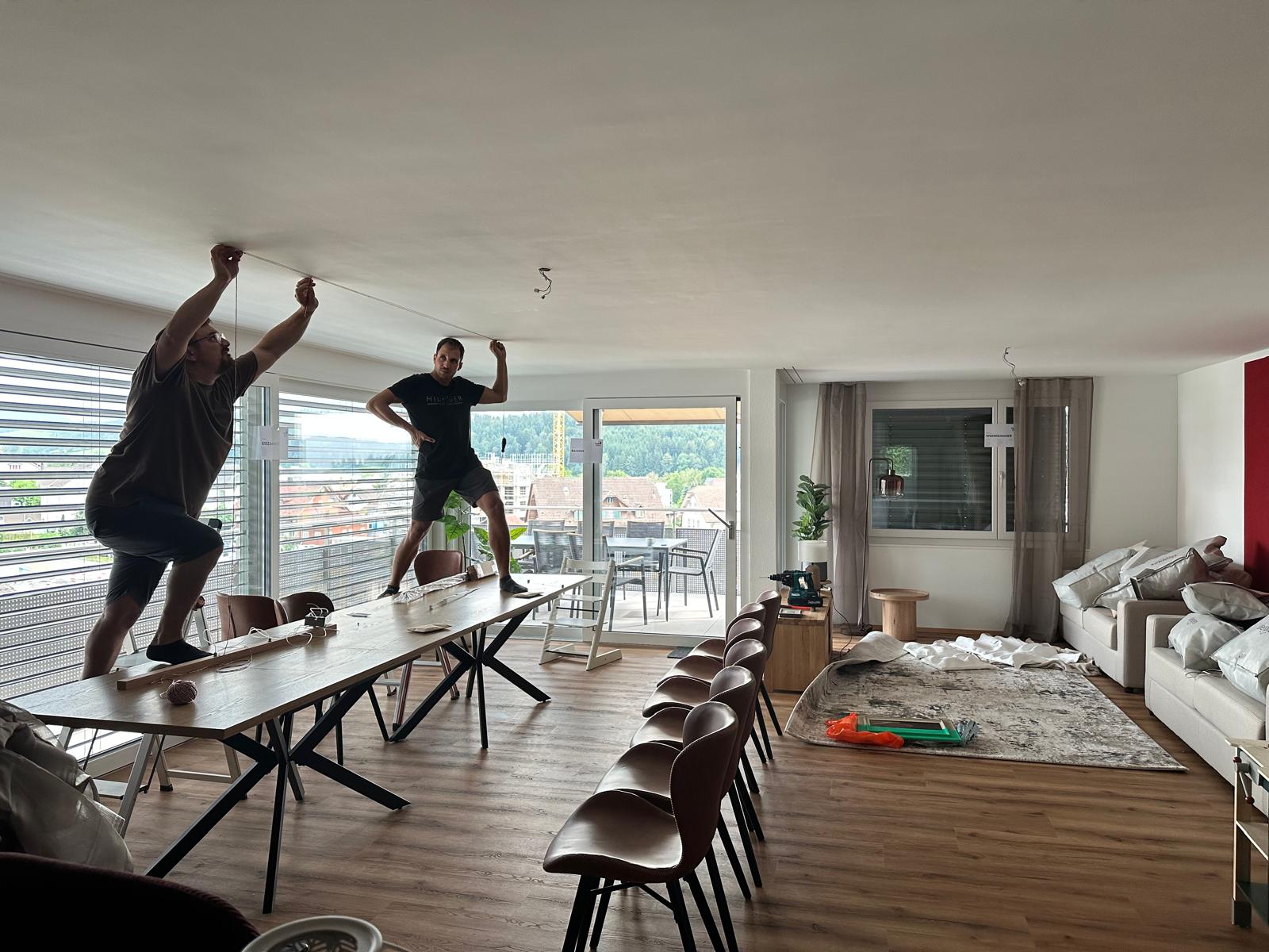 Zwei Männer stehen auf einem Esstisch, um an der Decke zu arbeiten